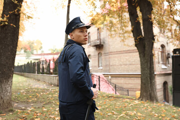Police officer in bulletproof vest with baton at park. Space for text