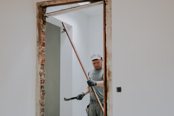 A man working with a crowbar in a doorway.
