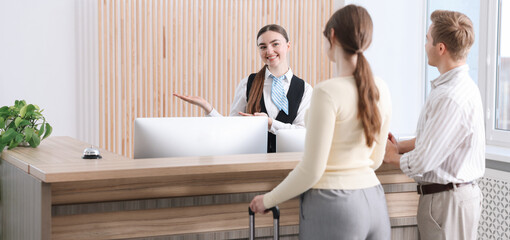 Receptionist welcoming guests at reception desk in hotel