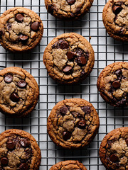 Freshly baked chocolate chip cookies cooling on a wire rack in a cozy kitchen setting