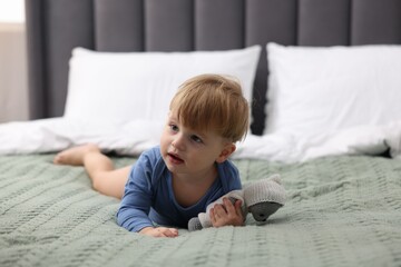Fototapeta premium Cute little child with toy lying in bed indoors