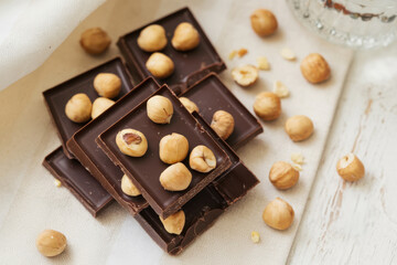 Dark chocolate squares with pecans and hazelnuts, plated gourmet dessert, premium snack, festive minimal composition, elegant closeup, healthy food, modern indulgence