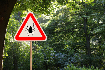 Warning sign marking habitat of ticks in forest