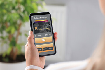 Online payment. Woman using banking app on smartphone indoors, closeup