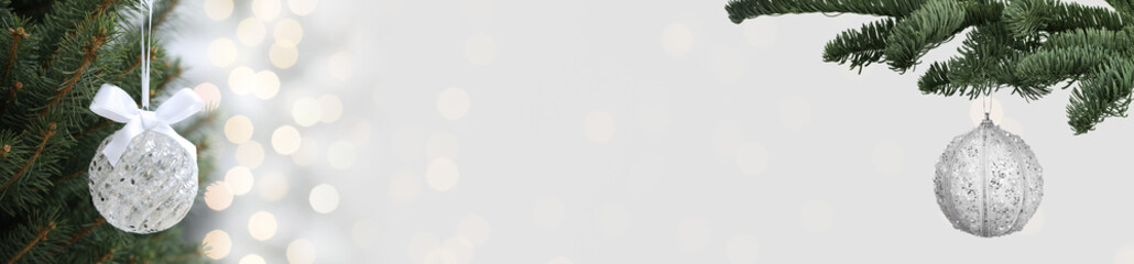 Christmas balls and fir tree branches on white background, bokeh lights. Banner design