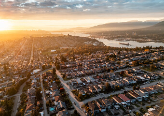 Golden Sunset Over A Burnaby Suburb With River, Hills, And Dense Residential Grid At Dusk