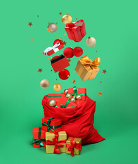 Christmas balls, gift boxes and confetti falling into bag on green background