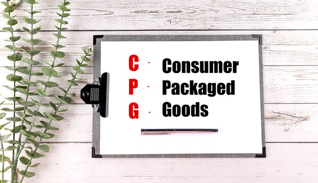 Acronym CPG meaning consumer packaged goods written on clipboard with pen and green leaves
