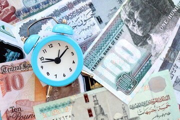 Egyptian pound currency money bills and alarm clock close up. The concept of time management and income