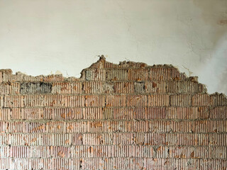 Peeling white plaster exposing red brick underneath, with crumbling edges and textured decay, evoking aged urban architecture and rustic charm