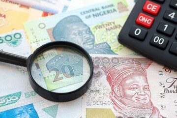 Nigerian naira currency money bills and calculator with magnifying glass close up. The concept of taxation and money count