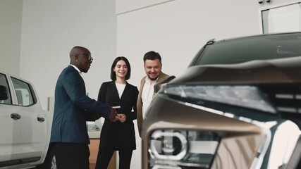 A man and woman consult with an African car dealer in a modern showroom about choosing a new vehicle. Concept assisting in car selection.