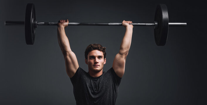 Young man performs overhead lift with a barbell in a dark gym setting during strength training session for fitness Generative AI - Powered by Adobe