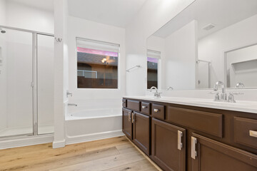 A spacious bathroom with two sinks, a bathtub, and a shower