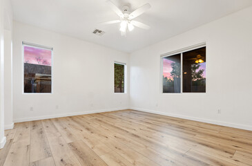 Spacious empty living room with hardwood floors and ceiling fan