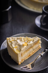 Sweet creamy cake on plate on black table.