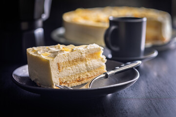 Sweet creamy cake on plate on black table.