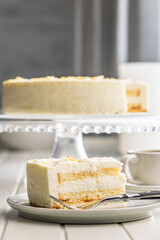 Sweet creamy cake on plate on white table.