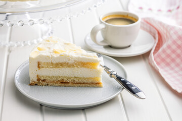 Sweet creamy cake on plate on white table.