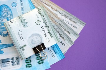 United Arab Emirates dirham money bills in big amount close up on purple. Finance and banking concept