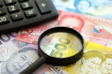 Philippines peso currency money bills and calculator with magnifying glass close up. The concept of taxation and money count