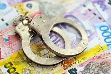 Philippines peso currency money bills and handcuffs close up. The concept of criminal