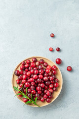 Fresh cranberries in a wooden bowl on a light background. Concept of healthy natural wild berries.