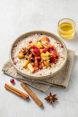  Overnight oatmeal with apple, cranberry and cinnamon in a plate on a light background with honey and spice.
