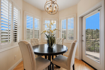 A dining room with a table, chairs, and a window with shutters