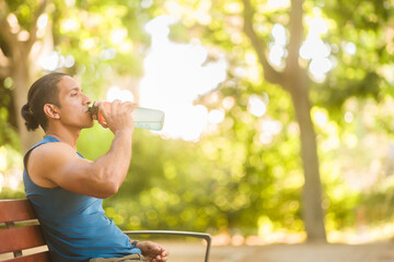 Venezuelan athlete hydrating during outdoor training on bench