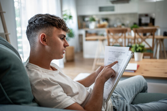 Teenager boy studying homework at home on couch