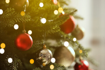 Christmas balls hanging on fir tree, closeup. Bokeh lights. Greeting card design