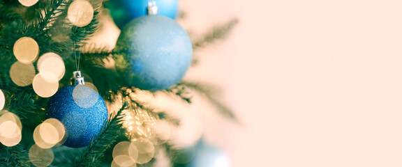 Christmas balls hanging on fir tree on beige background, closeup. Bokeh lights. Greeting card design