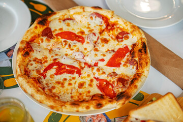 A pizza with cheese and red peppers sits on a white plate