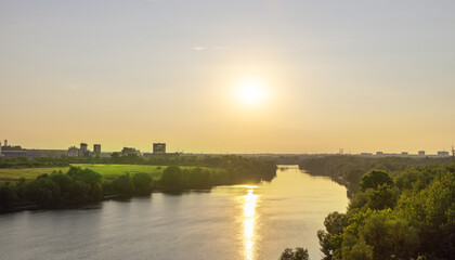 Obraz premium The sun is setting over a river, casting a warm glow on the water