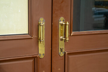 Close-up of old brass door handles with patina on a brown wooden front door. Vintage background for the concept of entrance, security, opportunity, and decision making for the future.