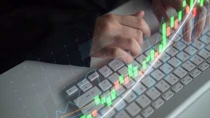 Close-up of hands typing on a computer keyboard with a dynamic stock market chart overlay, representing the intersection of technology and finance in trading activities. Copula