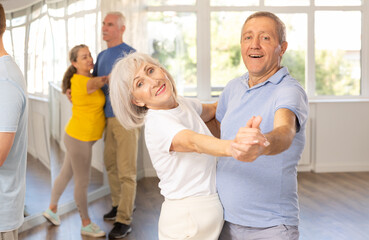 Elderly man and elderly woman dance ballroom dance waltz in studio