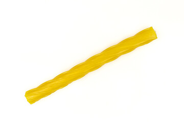 Single yellow gummy licorice stick isolated on white background. Chewy liquorice treat