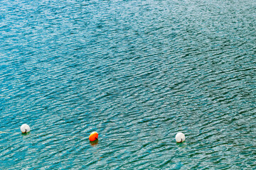 Colorful buoys float on calm water with gentle ripples in a serene outdoor setting