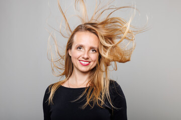 Woman celebrating success with flowing hair and a radiant smile in a modern studio during the day