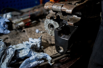 Repaired hydraulic machinery component on workshop table with tools and paper wipes showing industrial maintenance process, metal assembly precision and mechanical restoration work