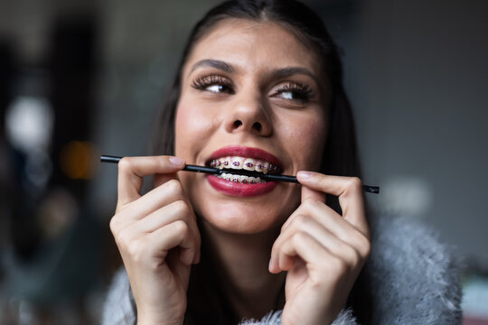 Smiling woman with dental braces holding a black straw, expressing happiness and confidence