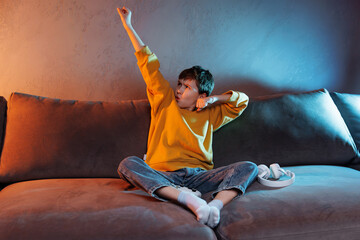 Young child in cozy yellow sweater sits on a sofa, striking a heroic pose with a determined...