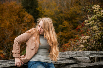 casual outdoor scene with thoughtful lady, pensive blonde woman seated near golden leaves