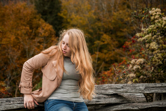 casual outdoor scene with thoughtful lady, pensive blonde woman seated near golden leaves - Powered by Adobe