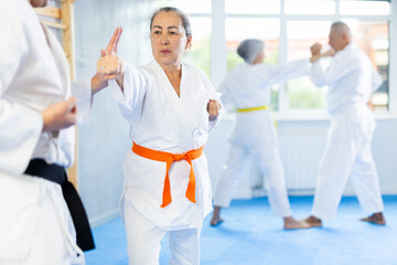 Senior karate practitioner engage in fierce fight, perseverance during martial arts discipline, middle-aged teacher and mature followers. Work on yourself, increase endurance, determination, courage