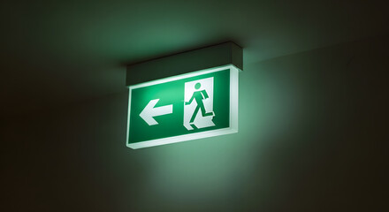 Green Illuminated Emergency Exit Sign with Arrow Pointing Left