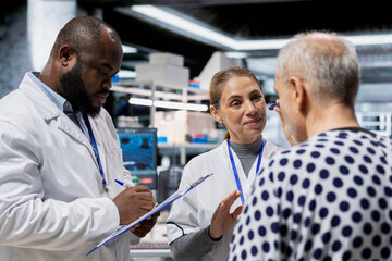 Obraz premium Diverse researchers team monitoring patient reactions during drug testing, documenting dosage response and treatment progress to advance pharmacology and safety. Innovation in medicine.