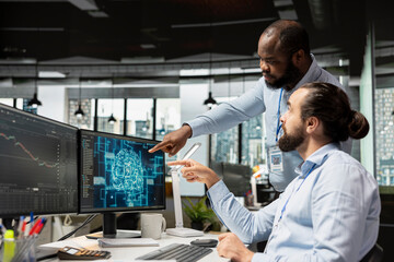 Team of day traders using AI technology on PC capitalize on market fluctuations when buying and selling stocks. Prop firm office colleagues use machine learning to identify fast profit opportunities